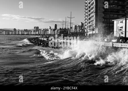 Santos City, Brasilien. September. Wellen krachen an Land während der Winterflut. Strandmauer und Gebäude am Wasser. Stockfoto