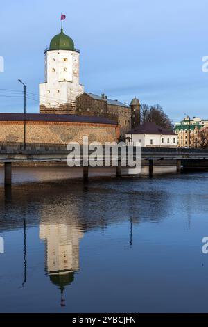 Schloss Vyborg an einem sonnigen Wintertag. Russland. Vertikales Foto mit Reflexionen in stillem Wasser Stockfoto