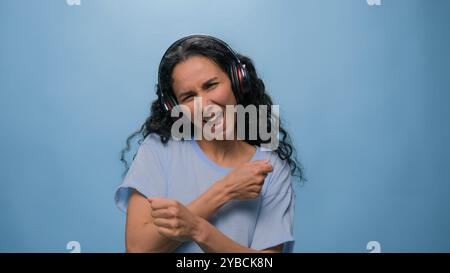 Studio-Porträt glücklich lächelnd singend Arabische Frau indische Dame Hispanic Mädchen hört Musik mit Kopfhörern Tanzen Hören Radio Tanz Bewegung auf Stockfoto