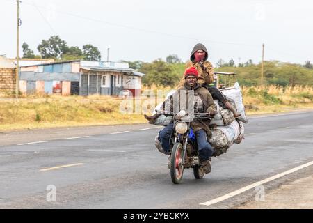 Motorrad mit Fahrer und Beifahrer, mit großen Taschen als Ladung, auf der Hauptstraße in der Nähe von Nairobi, Kenia, Afrika Stockfoto