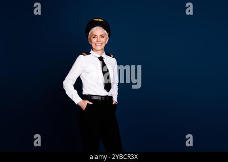 Foto-Porträt der attraktiven älteren Frau Passagierflugkapitän selbstbewusst gekleidete Fliegeruniform isoliert auf dunkelblauem Farbhintergrund Stockfoto