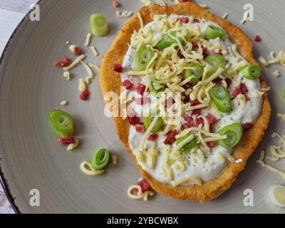 Ungarische Langos mit Knoblauchcreme, Speck, Frühlingszwiebeln und Käse Stockfoto