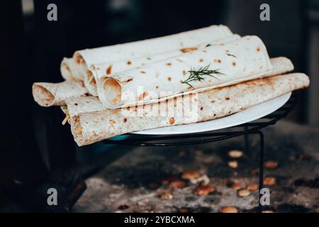 Fladenbrot gerollt und mit Käse und Gemüse gefüllt. Grillzubereitung im Freien. Vegetarisches Streetfood auf einem Metallgitter aus nächster Nähe. Stockfoto