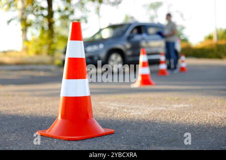 Der Prüfer, der den Schüler vor der Prüfung auf der Fahrschule anweist, konzentriert sich auf den Verkehrskegel Stockfoto