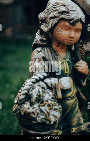 Abgenutzter Steinengel. Alte weibliche Figur mit schäbiger Farbe im Gesicht. Denkmal auf einem Friedhof. Alte Statue aus nächster Nähe. Traurigkeit, Sehnsucht, Depression. Stockfoto