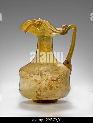 Oinochoe, 3.-4. Jahrhundert n. Chr. zusätzliche Info: Frei geblasene Oinochoe aus gelbem lichtdurchlässigem Glas. Der Körper des Gefäßes ist zylindrisch und sieht aus wie ein Overblow. Der Mund hat einen Auslauf aus Dreireifen mit einer dicken Spur, die unter dem Rand angebracht und auf einer Seite in einer Spirale verbunden ist. Der Griff verbindet die Schulter mit dem Rand. Das Gefäß hat einen kleinen Ringboden mit einer Pontil-Markierung an der Unterseite. Sie ist innen nur leicht verwittert. Stockfoto