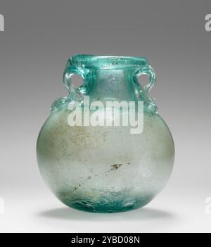 Aryballos, 1.-2. Jahrhundert n. Chr. zusätzliche Info: Ein freigeblasenes Aryballos aus blau-grünem Glas. Die Felge wird über die Innenkante gefaltet. Zwei „Delfin“-Griffe sind als gewellte Gewinde angebracht, die so gefaltet werden, dass sie kleine Schlaufen unter dem Rand bilden. Am Boden befinden sich große Blasen und innen etwas Inkrustation. Stockfoto
