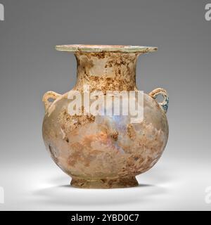 Amphoriskos, 1.-2. Jahrhundert n. Chr. zusätzliche Info: Das Schiff ist breit und kräftig und wurde aus farblosem Glas freigeblasen. Er hat einen konischen Fuß und einen abgefackelten Rand. Zwei winzige Griffe werden aufgebracht und umgefaltet; einer davon ist aus einem anderen blau-grünen Glas. Auch aus blau-grünem Glas wird ein Gewinde auf die Unterseite des Feldes aufgebracht, so dass es durch das farblose Glas des Feldes sichtbar ist. Der Großteil der Oberfläche ist verwittert, wodurch das Gefäß schillert und eine undurchsichtige, schmutzig-weiße Schicht erhält. Stockfoto