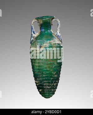 Amphoriskos, 1. Jahrhundert n. Chr. zusätzliche Info: Mold mold mold mold Amphoriskos aus dunkelgrünem Glas, in eine zweiteilige Form geblasen. Der konische Körper ist mit dreiundzwanzig horizontalen Graten verziert. Der kurze zylindrische Hals endet mit einem sich abflackernden Mund und nach innen gefalteter Lippe. Zwei kleine blaue Griffe wurden auf der Schulter angebracht und bis zum Rand gezogen. Dieser Amphoriskos ist stark verwittert und wurde mit großen Füllungen am Körper wieder zusammengebaut. Stockfoto