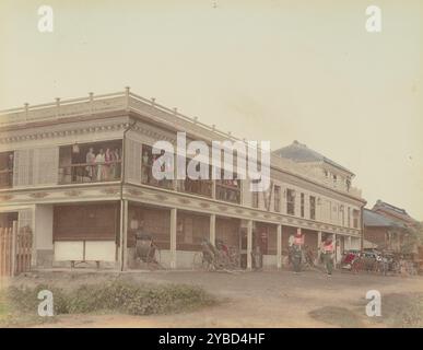 Geisha House, 1870er-1890er Jahre Großes, zweistöckiges Gebäude mit mehreren Frauen, die an den Fenstern im Obergeschoss stehen und Rikschas vor der Eingangstür geparkt haben. Stockfoto