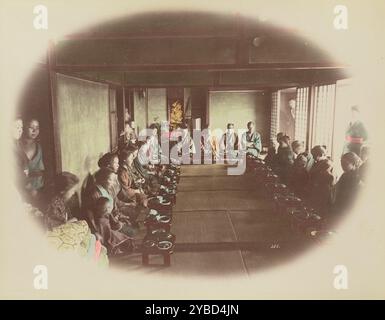 Essen zu Hause, 1870er-1890er Jahre Mehrere Personen, die in einem Rechteck angeordnet sind, auf dem Boden sitzen, mit einzelnen kleinen Essenstischen davor, als Teil der Gedenkstätte für einen kürzlich verstorbenen Verwandten. Stockfoto