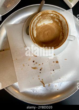 Übrig gebliebene Krümel von Croissant und fertige Kaffeetasse auf einem Metalltablett Stockfoto