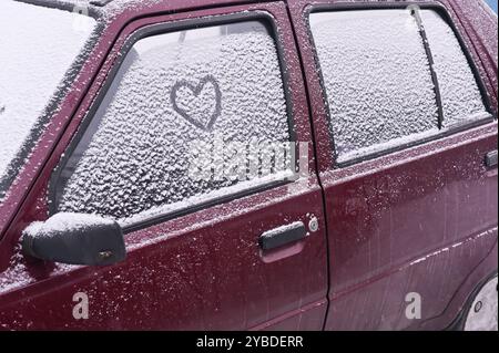 Ein Herz ist auf eine schneebedeckte Autoscheibe gemalt Stockfoto