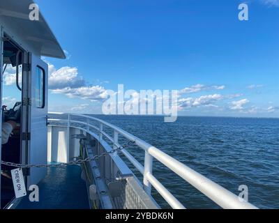 Passagiere genießen eine ruhige Fahrt mit der Fähre mit klarem Himmel und ruhigem Wasser an einem sonnigen Tag. Stockfoto