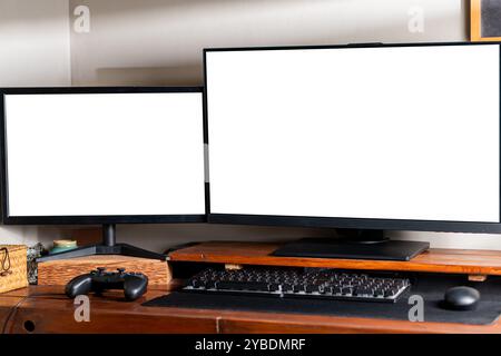 Zwei Computermonitore mit leeren Bildschirmen auf einem Holzpult, mit Tastatur und Gamecontroller. Stockfoto