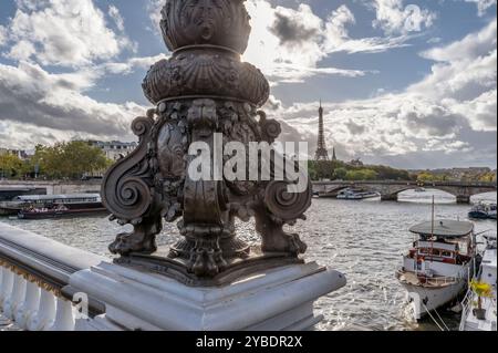 Die Sonne beleuchtet das Detail einer Straßenlaterne auf der Alexandre III Brücke in Paris, Frankreich, mit dem Eiffelturm im Hintergrund Stockfoto