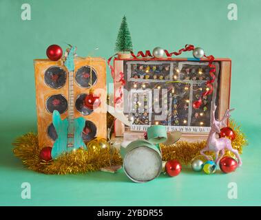 Musikinstrumente zu weihnachten mit schmuddeligen Pappmodellen von Musikinstrumenten, Synthesizer, Trommelset, Gitarre, Verstärker, Mikrofon und weihnachten Stockfoto