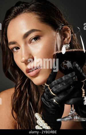 Eine schöne Frau in eleganter Kleidung genießt Rotwein, die Raffinesse und Charme versprüht. Stockfoto