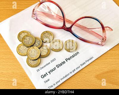 Ein offizieller Brief, in dem eine Person im Ruhestandsalter im Vereinigten Königreich mit einem Pfund Münzen und einer Lesebrille ihre Rente bekommen kann. Stockfoto