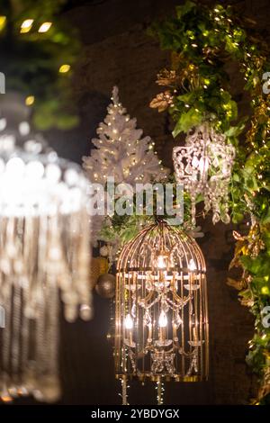 Funkelnde Lichter beleuchten eine wunderschön gestaltete Umgebung mit einem Kronleuchter, einem weißen Weihnachtsbaum und üppigem Grün und schaffen so ein festliches Ambiente Stockfoto