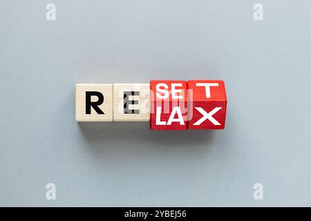 Reset-Symbol. Durch Drehen von Holzwürfeln wird das Wort „Reset“ in „Relax“ geändert. Schöner grauer Hintergrund, Konzept der Entspannung und frische Perspektive im Bus Stockfoto