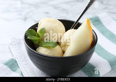 Löffel leckeres Melonensorbet mit Minze und Löffel auf weißem Tisch, Nahaufnahme Stockfoto