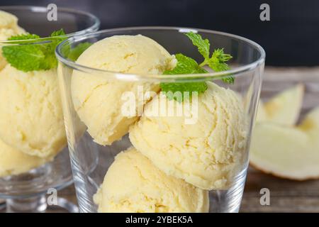 Löffel Melonensorbet und Minze in Dessertschalen aus Glas auf dem Tisch, Nahaufnahme Stockfoto