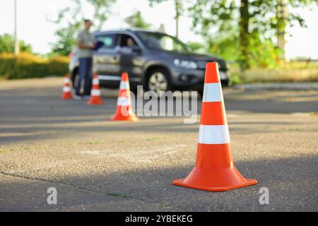 Der Prüfer, der den Schüler vor der Prüfung auf der Fahrschule anweist, konzentriert sich auf den Verkehrskegel Stockfoto