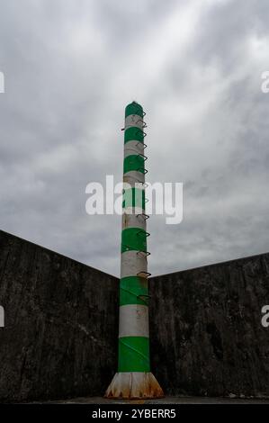 Ein grün-weiß gestreifter Turm steht hoch vor einem bewölkten Himmel in Seixal und steht im Kontrast zum bewölkten Wetter Stockfoto