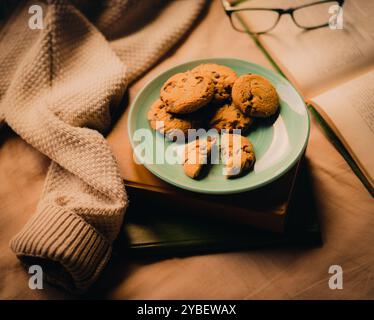 Eine gemütliche Lesesitzung mit einem Lieblingsbuch, begleitet von einem Teller köstlicher frisch gebackener Schokoladenkekse. Das ist Hygge von seiner besten Seite. Stockfoto