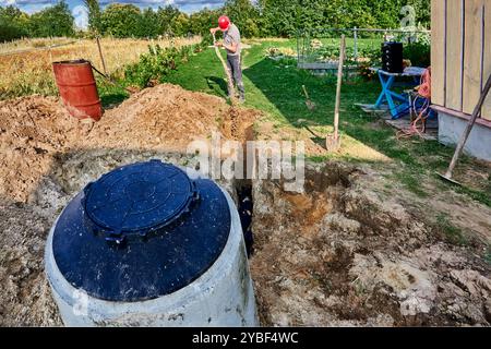 Arbeiter vergräbt einen saugfähigen Graben der Abwasserentsorgungsfläche des ländlichen Hauskanals. Stockfoto