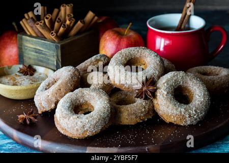 Chia Obstgarten Donuts auf einem Holzbrett mit heißem Apfelwein dahinter. Stockfoto