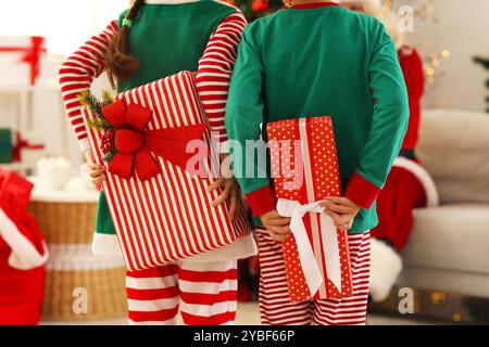 Kleine Elfen verstecken Weihnachtsgeschenke vor dem Weihnachtsmann zu Hause, Rückansicht Stockfoto