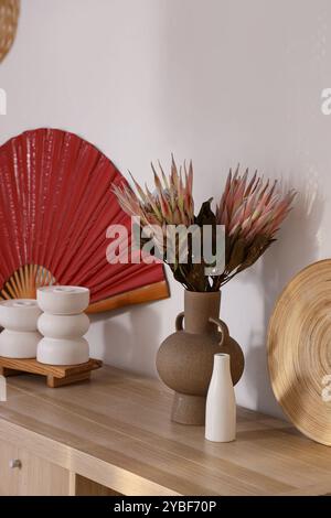 Holzschrank mit rotem Ventilator, Dekor und getrockneten Blumen im Wohnzimmer. Chinesisches Neujahrsfest Stockfoto