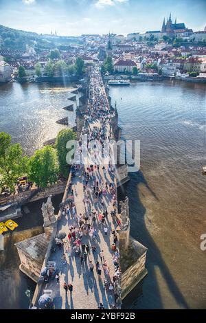 PRAG - 10. MAI 2024: Touristen wandern auf der Karlsbrücke in Prag mit Prager Burg und Moldau im Hintergrund an sonnigen Sommertagen Stockfoto