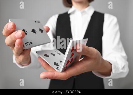 Professioneller Croupier, der Karten auf grauem Hintergrund mischt, Nahaufnahme Stockfoto