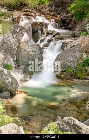 Ruhiger Wasserfall, der zwischen Felsbrocken in den Schweizer Alpen bei Monte Rosa fließt Stockfoto