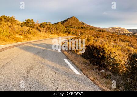 Straße bei Sonnenaufgang mit einer dunkleren Linie von neuem Asphalt, die sich vom benutzten Asphalt abhebt, im Departement Var, Frankreich, Europa. Stockfoto