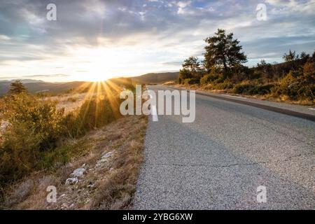 Straße bei Sonnenaufgang mit einer dunkleren Linie von neuem Asphalt, die sich vom benutzten Asphalt abhebt, im Departement Var, Frankreich, Europa. Stockfoto