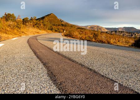 Straße bei Sonnenaufgang mit einer dunkleren Linie von neuem Asphalt, die sich vom benutzten Asphalt abhebt, im Departement Var, Frankreich, Europa. Stockfoto