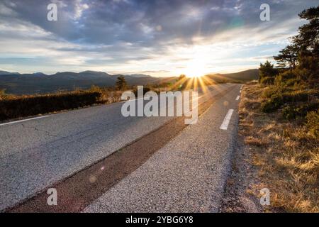 Straße bei Sonnenaufgang mit einer dunkleren Linie von neuem Asphalt, die sich vom benutzten Asphalt abhebt, im Departement Var, Frankreich, Europa. Stockfoto
