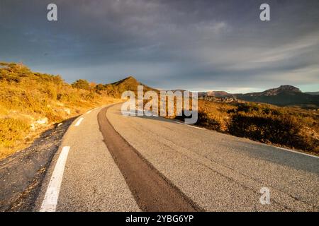 Straße bei Sonnenaufgang mit einer dunkleren Linie von neuem Asphalt, die sich vom benutzten Asphalt abhebt, im Departement Var, Frankreich, Europa. Stockfoto