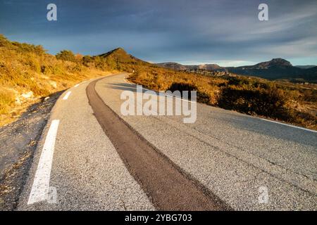 Straße bei Sonnenaufgang mit einer dunkleren Linie von neuem Asphalt, die sich vom benutzten Asphalt abhebt, im Departement Var, Frankreich, Europa. Stockfoto