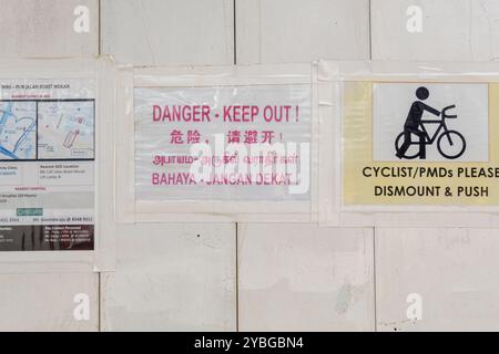 - Schild „Danger keep out“ in vier Sprachen - Malaiisch, Chinesisch, Thai, Englisch, Singapur - „Cyclists please dismount & Push“ Stockfoto