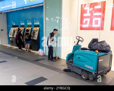 Frauen, die Geldautomaten benutzen, Singapur. Straßenkehrer, junger Mann, der arbeitet, Reinigungsmaschine Stockfoto