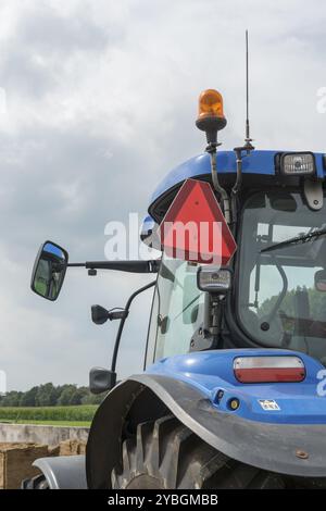 Blaue Traktor mit Details der abgeschnittenen Warndreieck für Kraftfahrzeuge mit einer begrenzten Geschwindigkeit auf der linken Seite Stockfoto