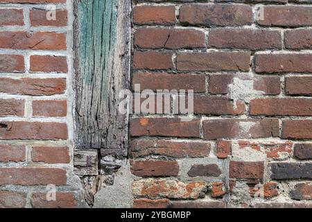 Hintergrundfoto einer alten Backsteinmauer mit kürzlich Restaurierung und verwitterte farbige Holzbalken Stockfoto