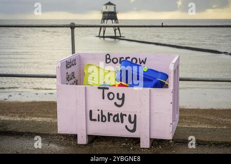 Eine Spielzeugbox mit dem Dovercourt Low Lighthouse im Hintergrund, gesehen in Harwich, Essex, England, Großbritannien Stockfoto