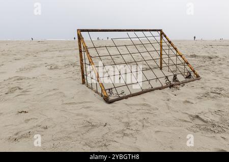 Verrostete Fußballtor an einem Strand mit Fischer auf dem Meer auf der Insel Terschelling in Niederlande Stockfoto