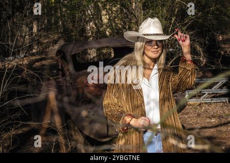 Ein prächtiges blondes Cowgirl-Modell posiert draußen und genießt dabei das Frühlingswetter Stockfoto